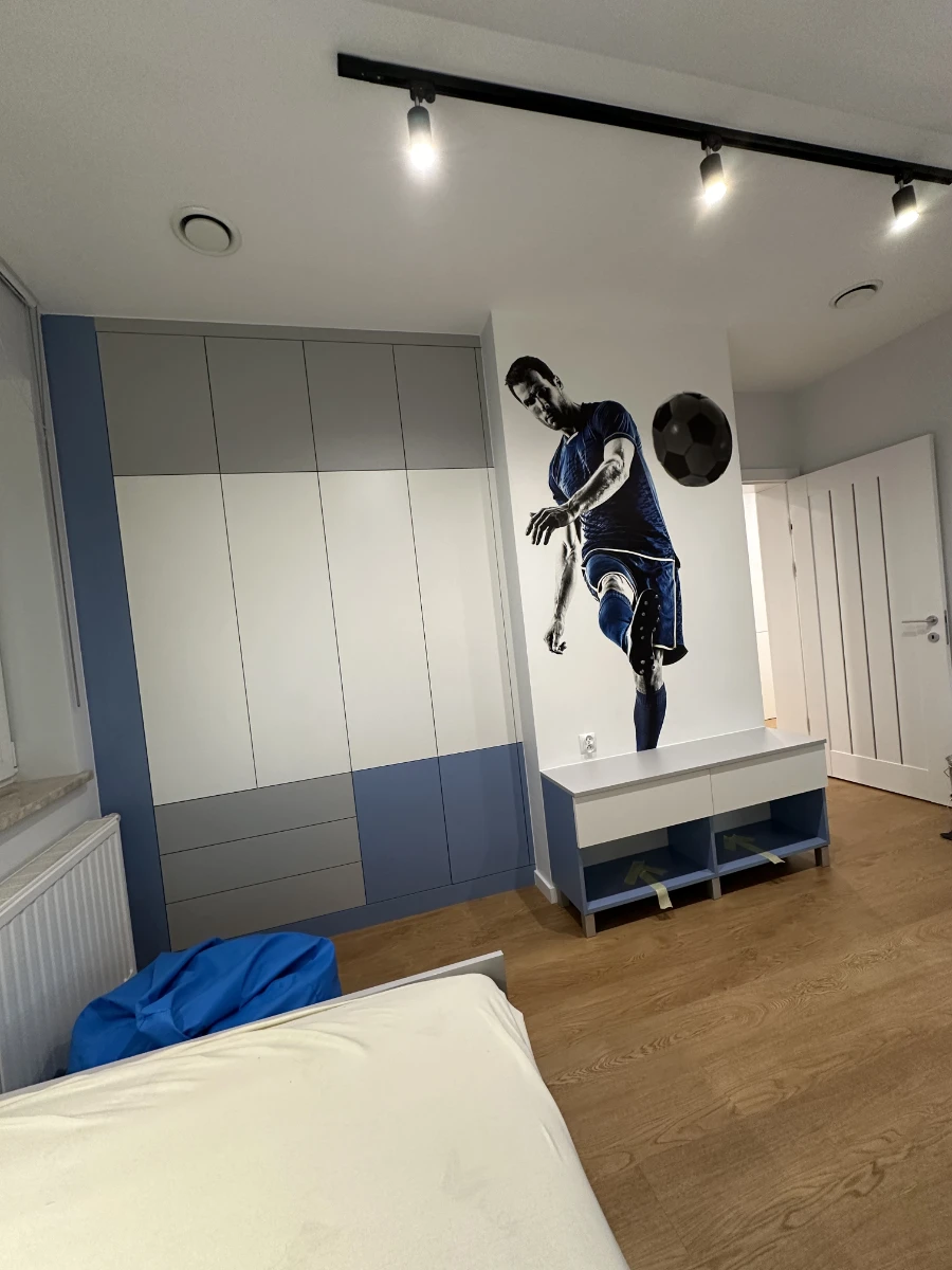 Sypialnia z intensywnym niebieskim akcentem i muralem piłkarza na ścianie