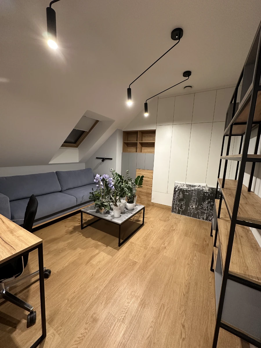 Przytulne poddasze z dużą ilością drewna i funkcjonalnym zagospodarowaniem przestrzeni