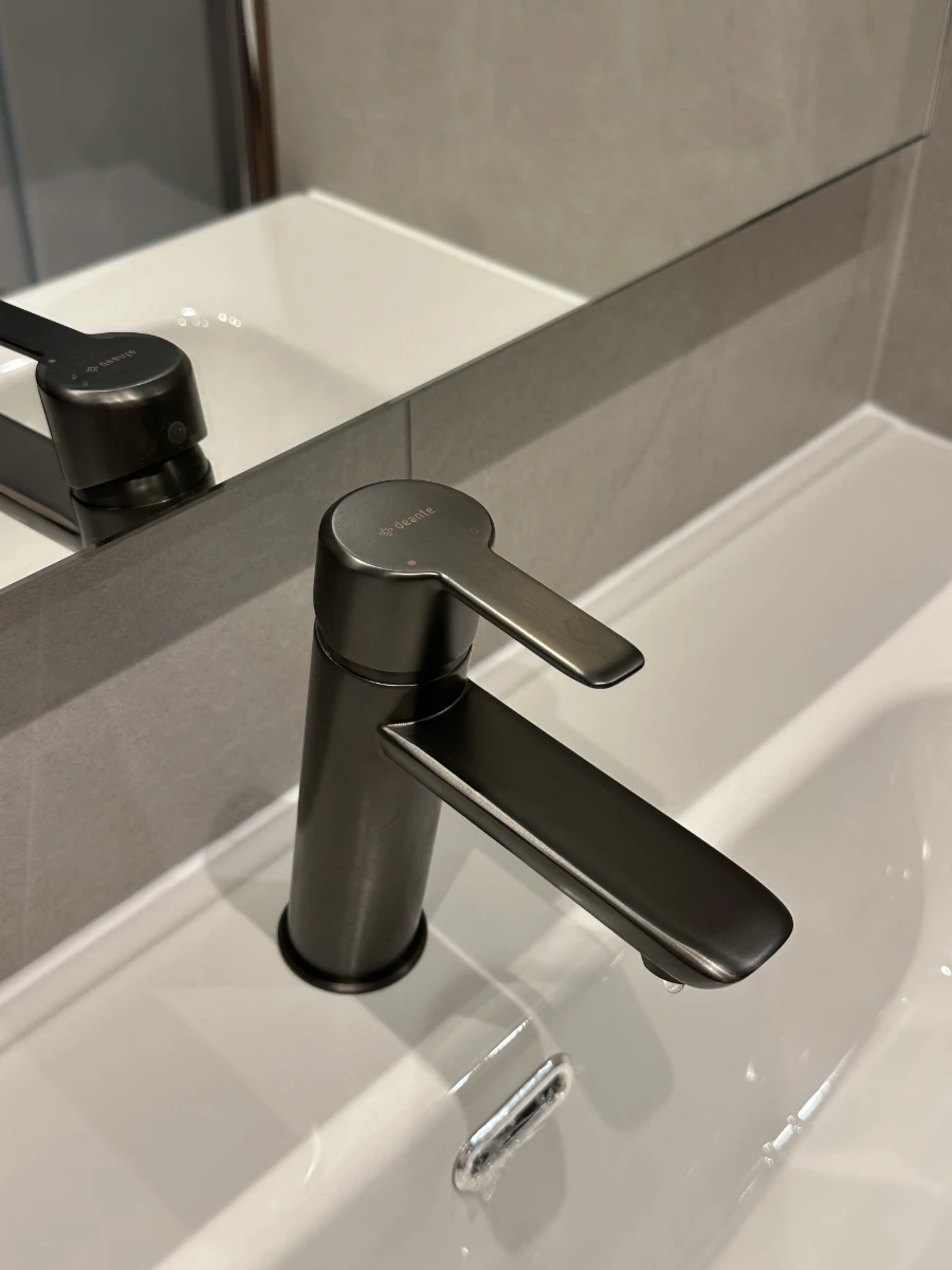 Czarny minimalistyczny kran łazienkowy na tle szarych płytek