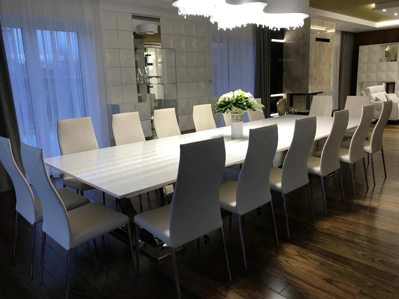 Jadalnia z długim białym stołem i wieloma białymi krzesłami